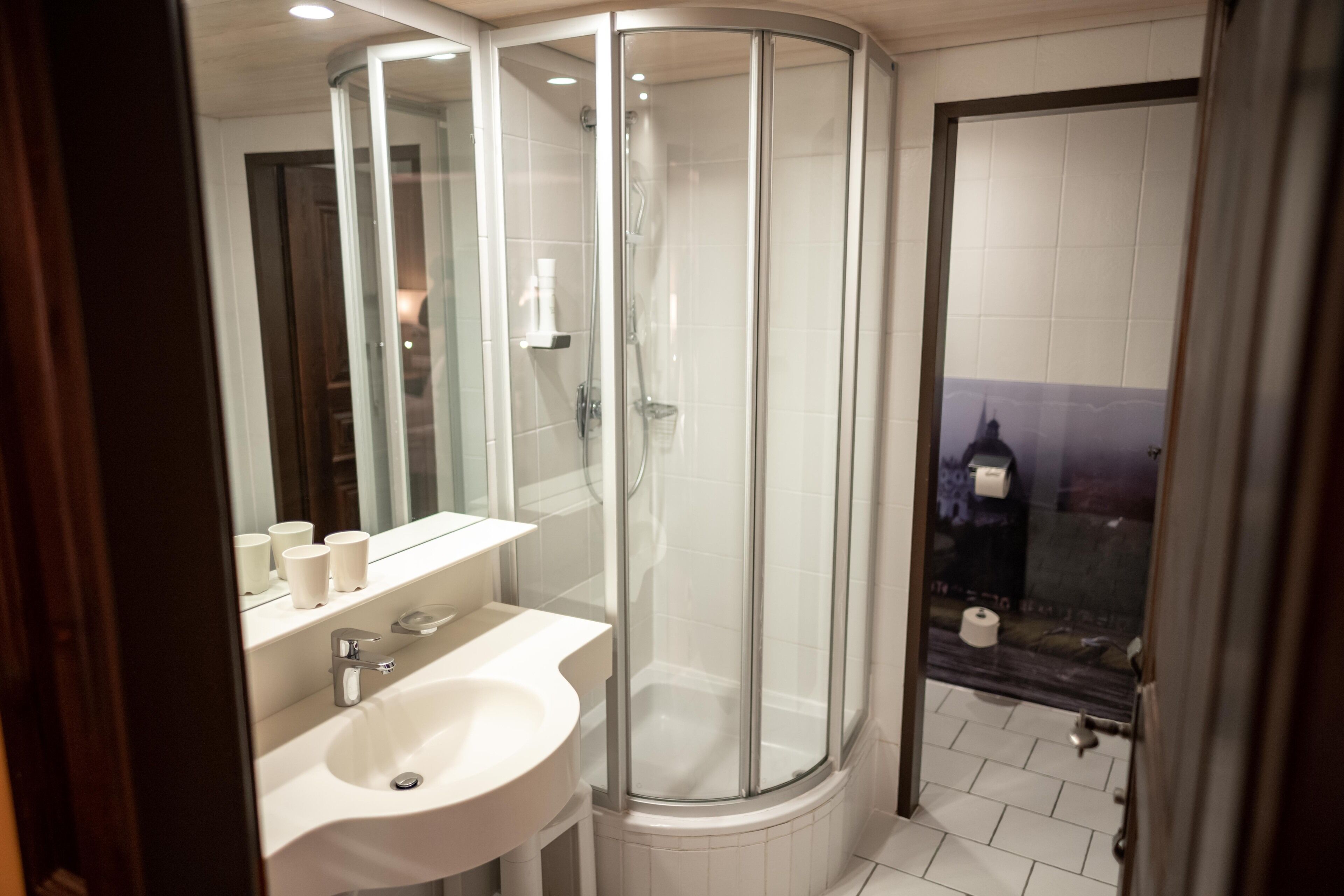 Une salle de bain avec une douche à parois de verre, un lavabo et un miroir.