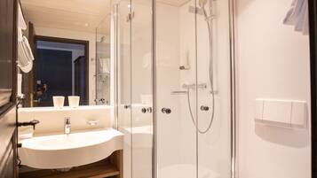 Un baño moderno con ducha de vidrio, lavamanos blanco y retrete.