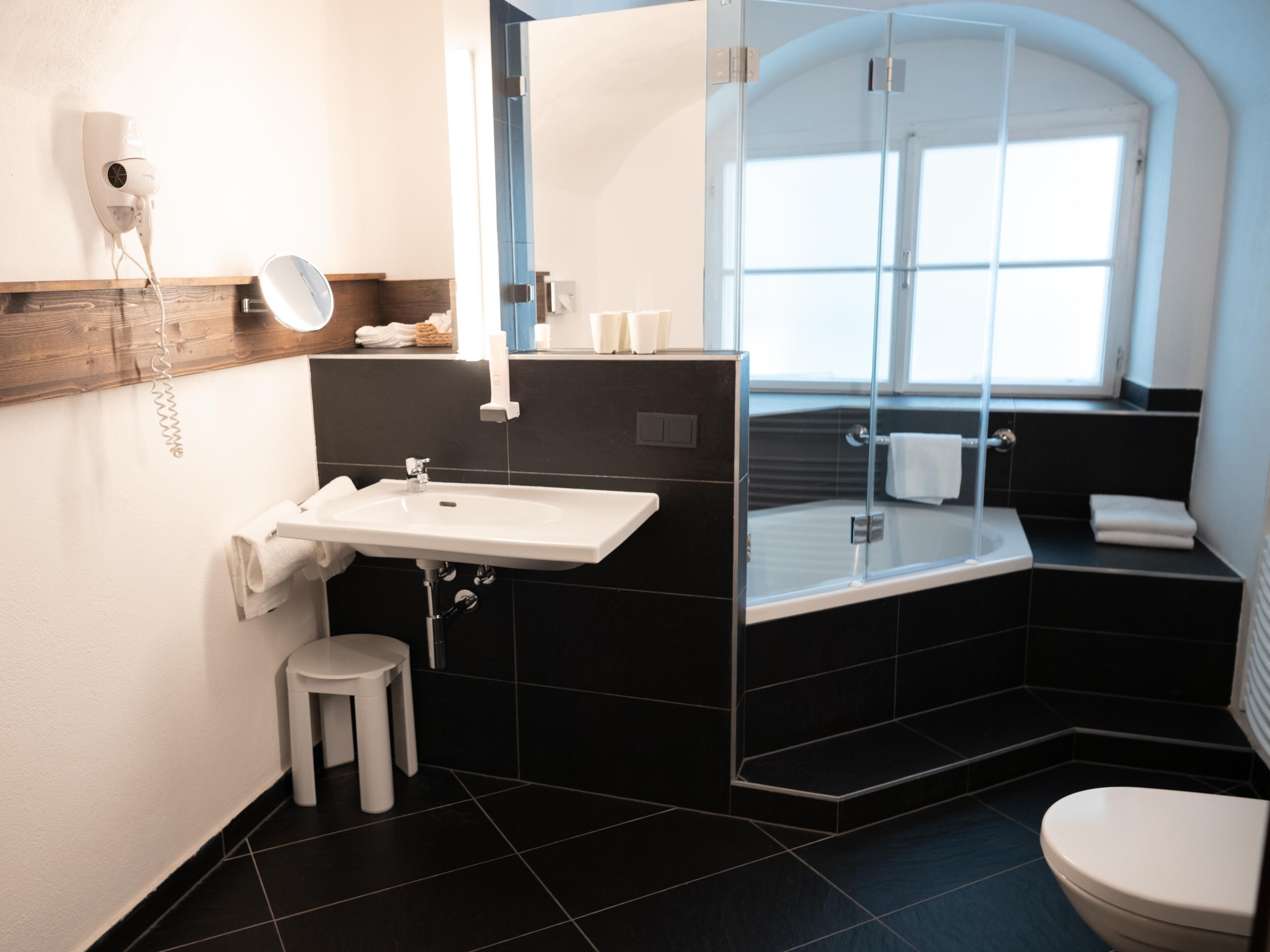 Een moderne badkamer met een witte wastafel, een spiegel, een toilet en een douche met glazen wanden.