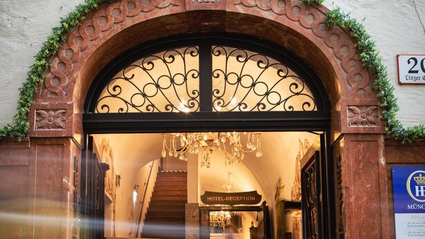 An entrance with a wrought iron gate, a reception desk, and a staircase leading inside. - Altstadthotel Stadtkrug (Salzburg)