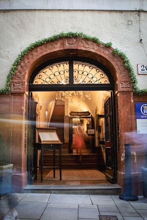 Una entrada con una reja de hierro forjado, un mostrador de recepción y una escalera que conduce al interior.