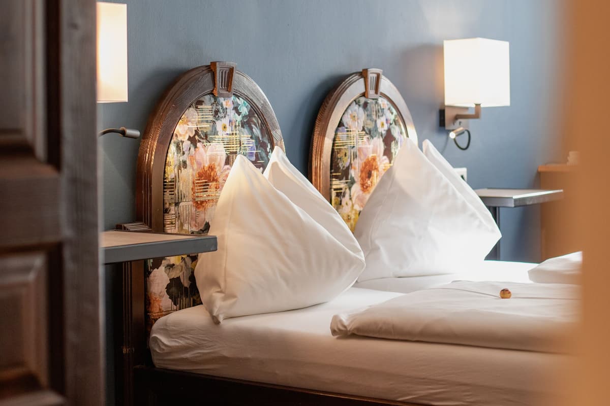A hotel room with a bed, two nightstands, and a wall-mounted lamp.