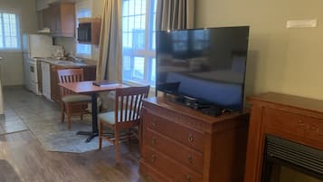 A compact kitchen with a dining area, a flat-screen TV, and a fireplace.