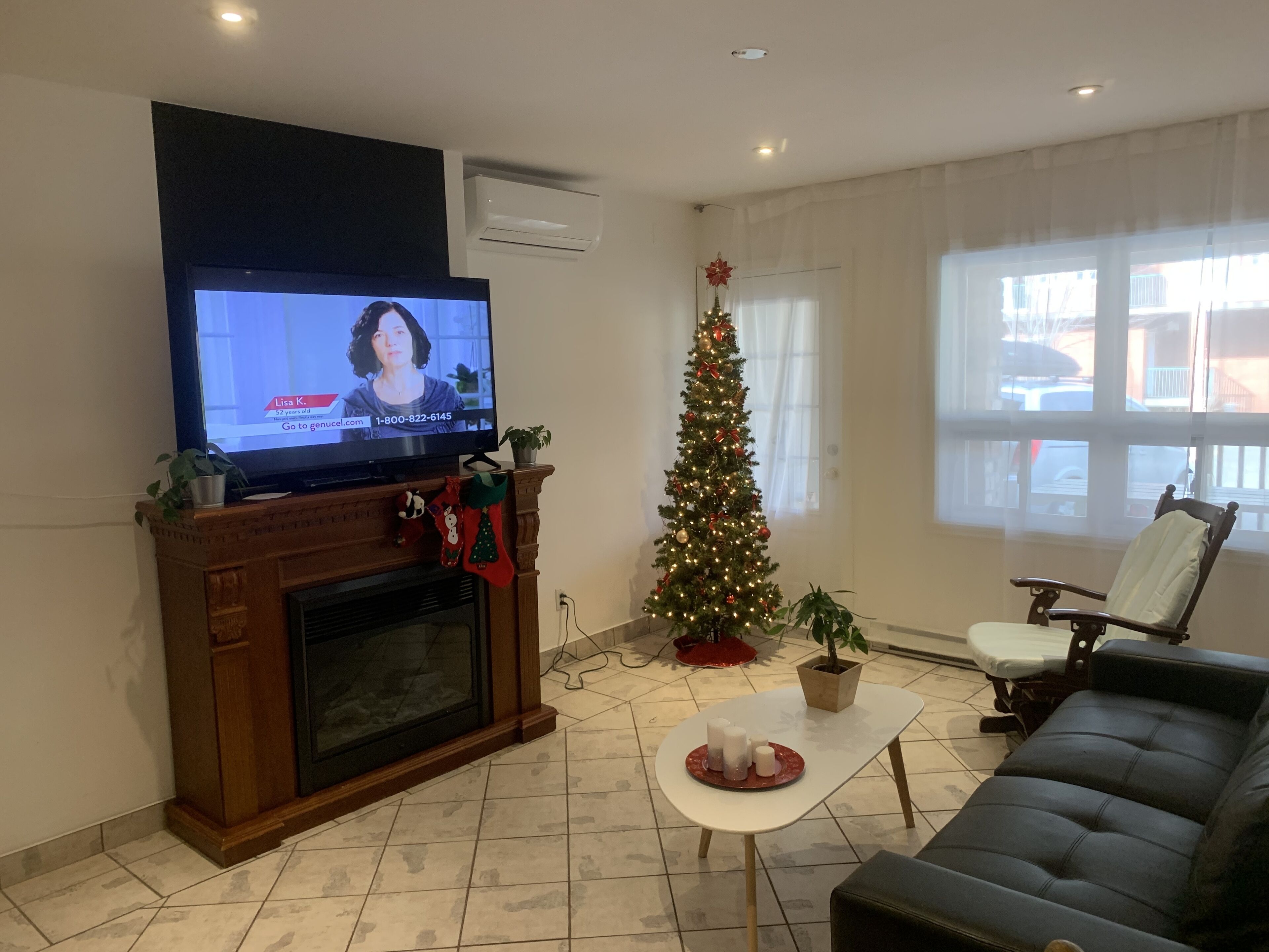 A living room with a fireplace, a television, a Christmas tree, and a sofa.