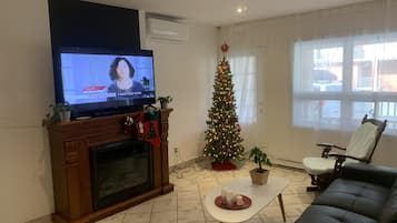 Una sala de estar con chimenea, televisor, árbol de Navidad y sofá.