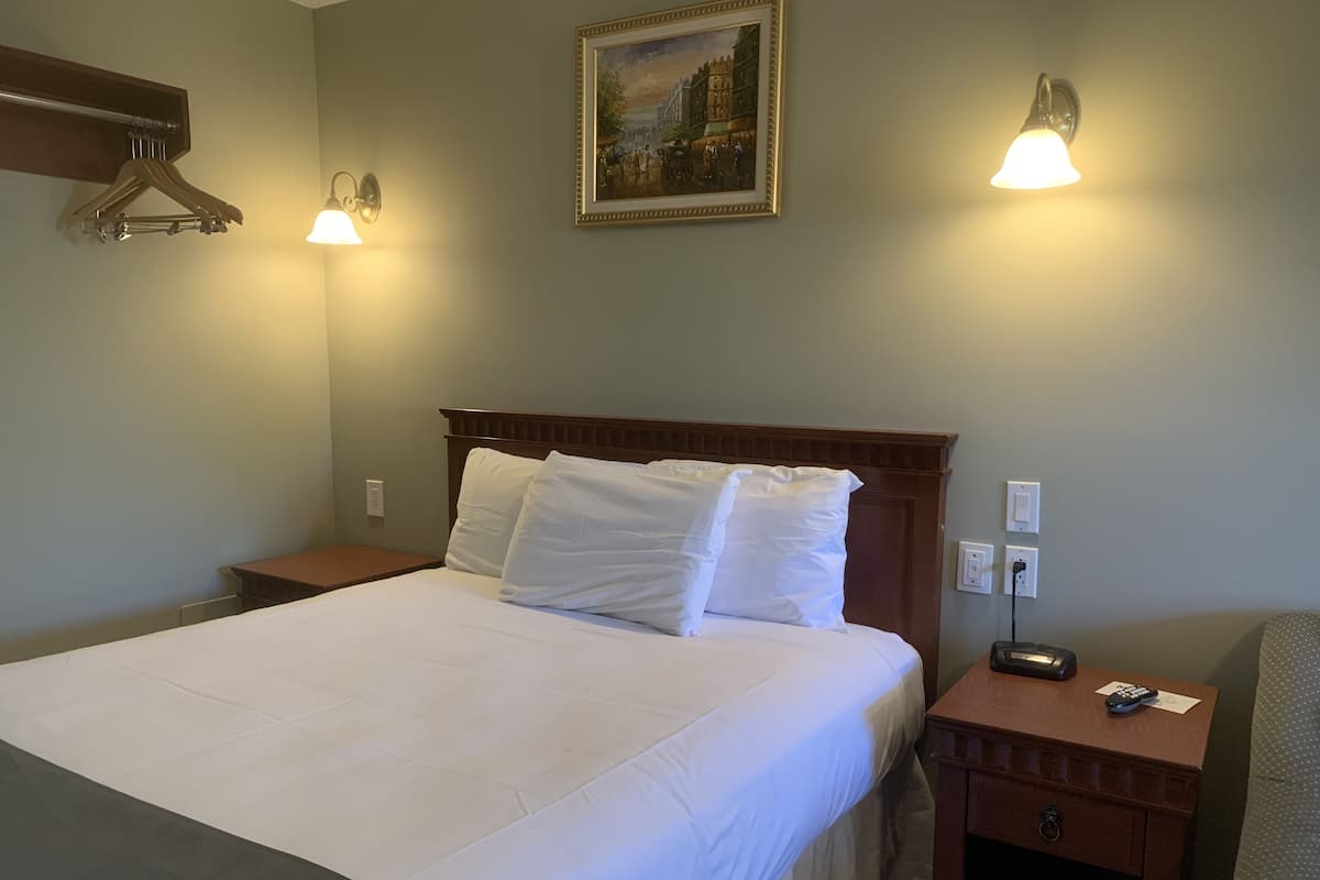 A neatly made bed with white linens, a wooden headboard, and two bedside lamps.