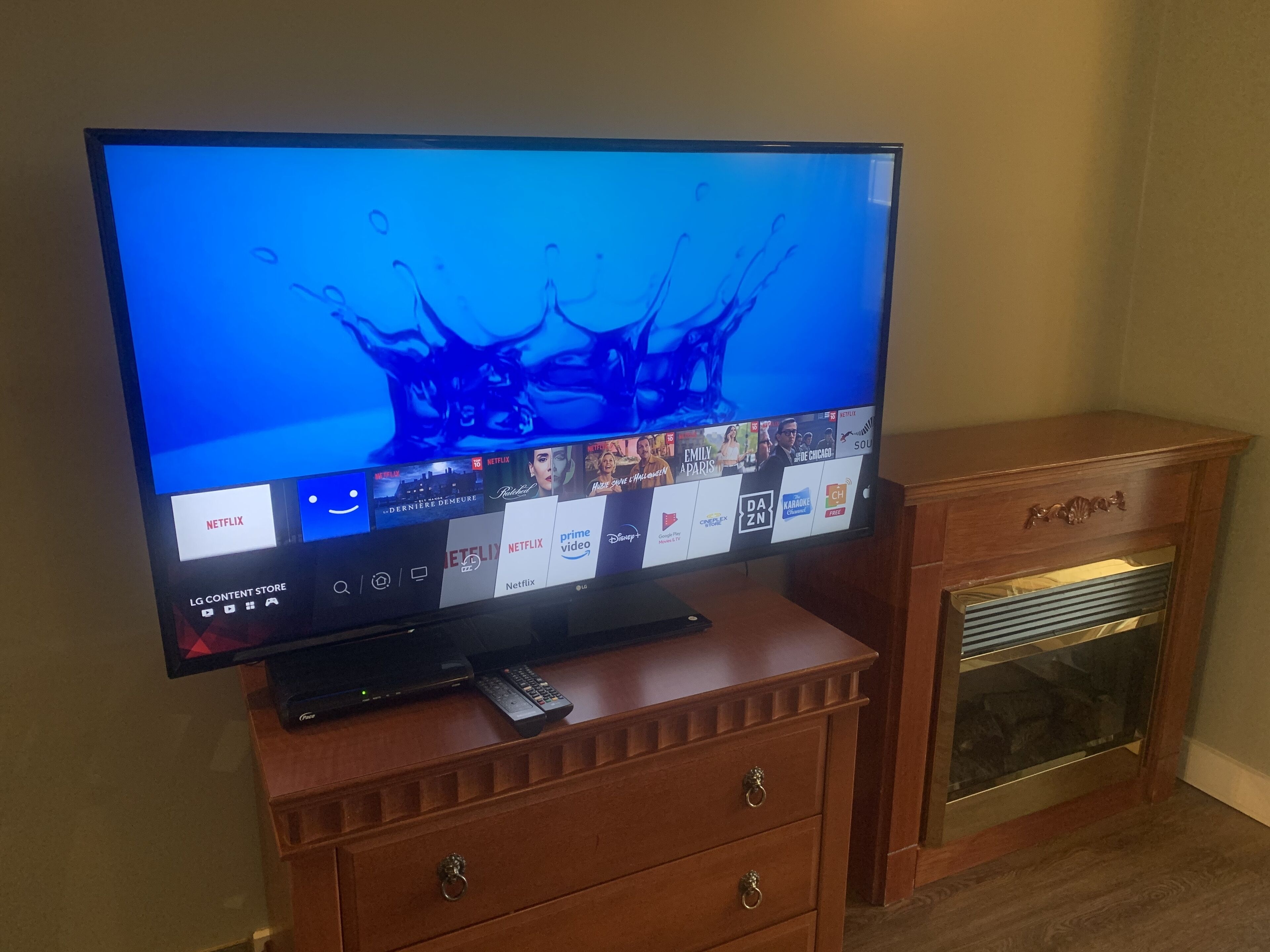 Un televisor de pantalla plana sobre un mueble de madera, con un control remoto a su lado.