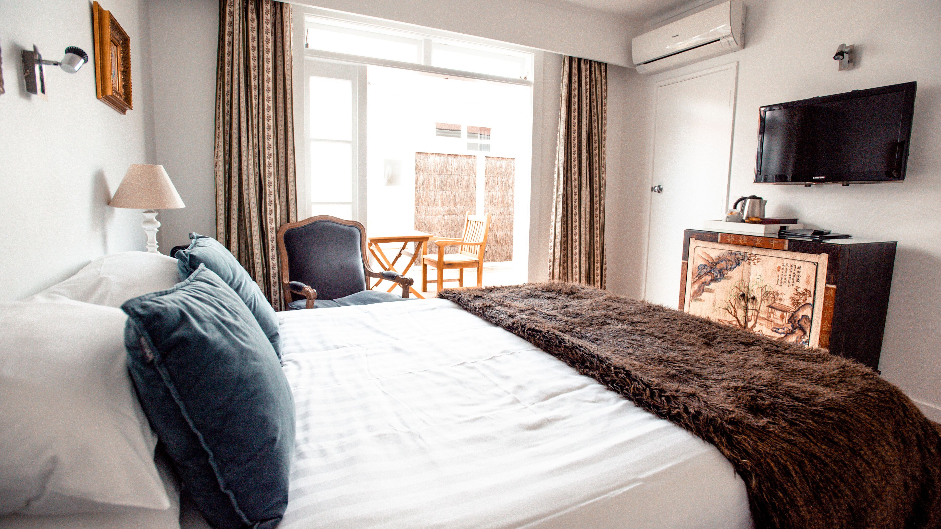 A hotel room with a bed, a chair, a desk, and a television.