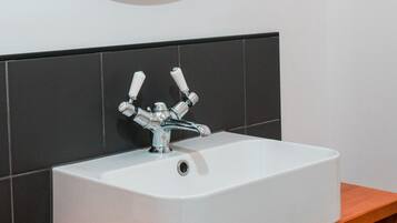 A bathroom with a white sink, a round mirror, and a wooden countertop.