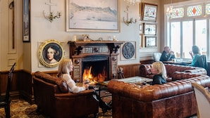 Un rincón tranquilo con sofás de cuero, una chimenea y un retrato grande en la pared.