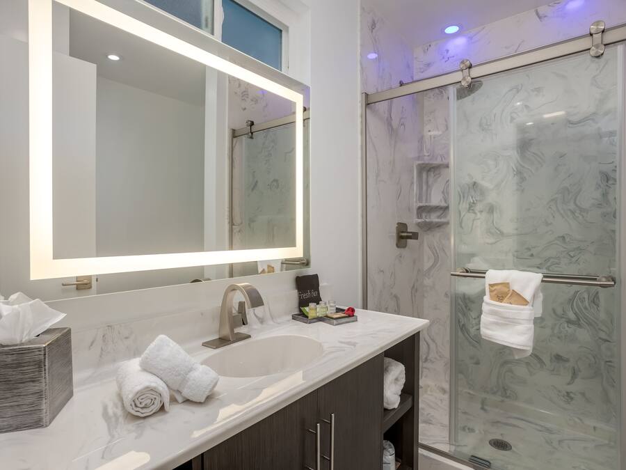 A modern bathroom with a large mirror, a sink, and a glass shower enclosure.