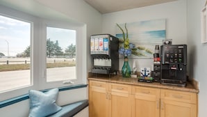 A kitchen with a coffee machine, a sink, and a window with a view of the outside.
