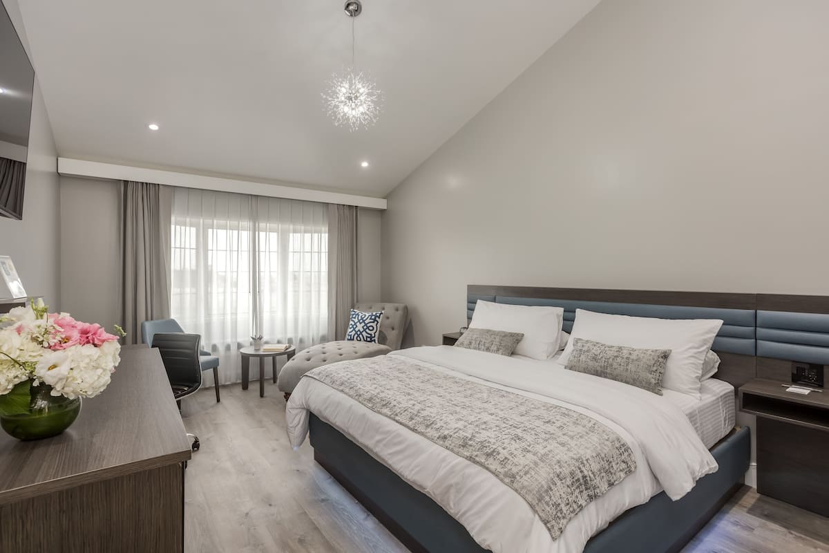 A modern bedroom with a large bed, bedside tables, a desk, and a chair.