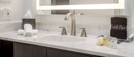 A bathroom with a large mirror, a sink, and a towel rack.