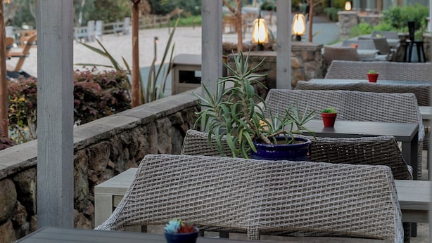 An outdoor patio area with wicker furniture and hanging light fixtures. - River Terrace Inn (Napa)