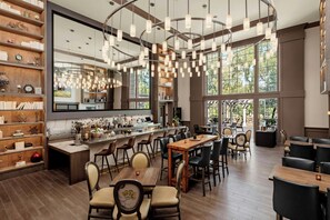 A spacious restaurant with a bar area, wooden furniture, and large windows. - River Terrace Inn (Napa)