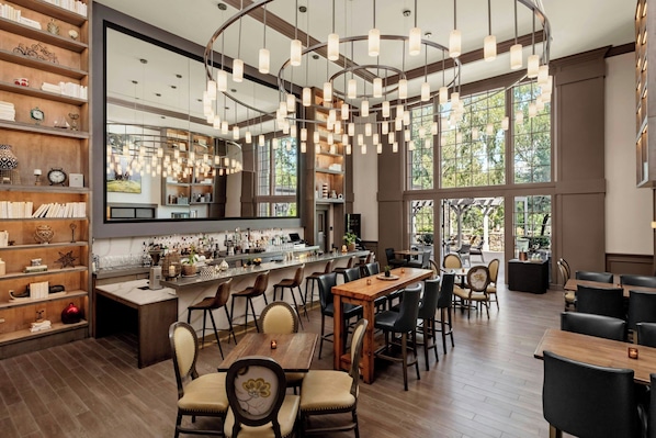 A spacious restaurant with a bar area, wooden furniture, and large windows.