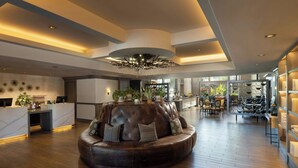 A spacious lobby with a central seating area, a reception desk, and a large chandelier. - River Terrace Inn (Napa)