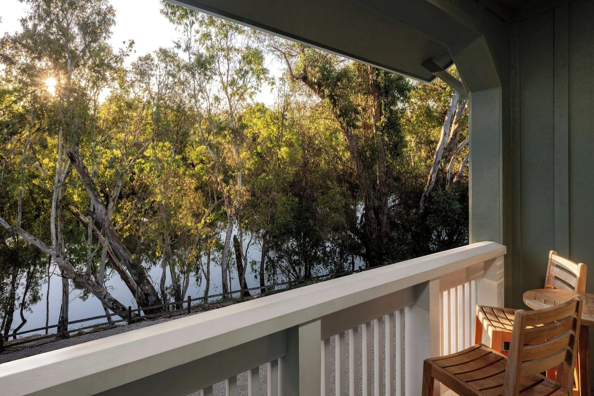 A balcony with a view of trees and a body of water.