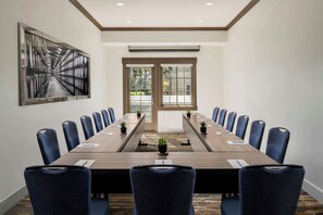 A conference room with a long table, blue chairs, and a large abstract painting on the wall.