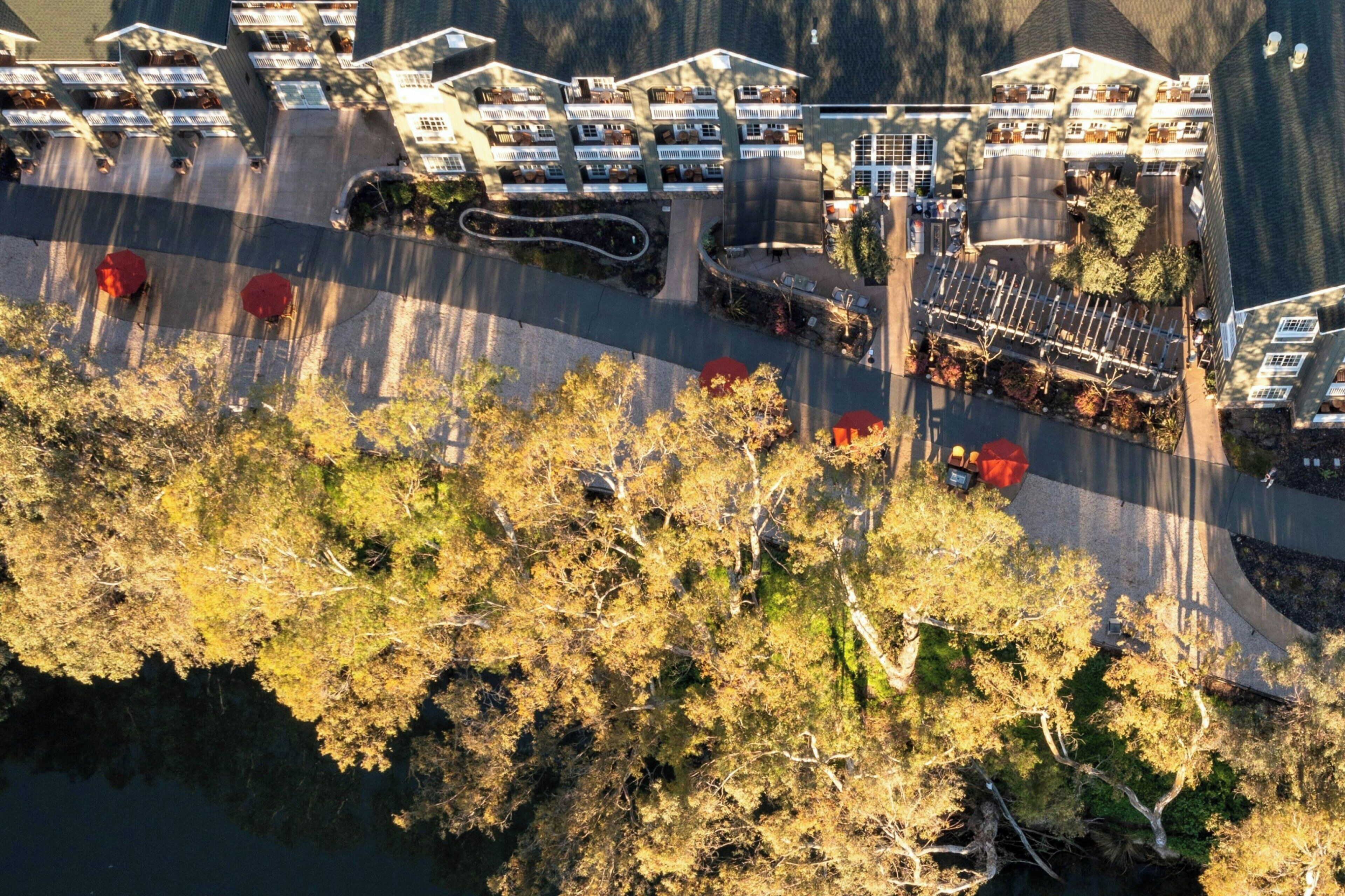 An aerial view of a hotel with multiple buildings, a parking area, and a body of water.