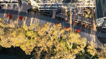 An aerial view of a hotel with multiple buildings, a parking area, and a body of water.