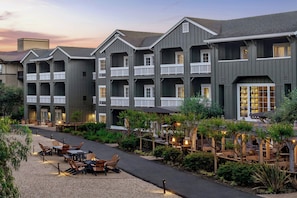 A multi-story hotel with balconies, outdoor seating, and a landscaped garden. - River Terrace Inn (Napa)