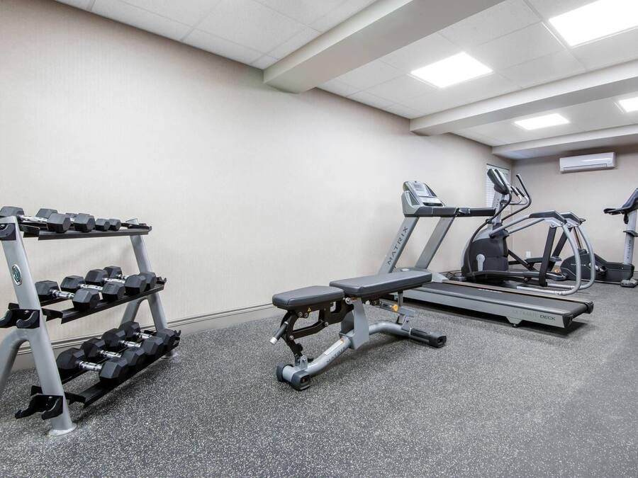 Un gimnasio con una prensa de banca, mancuernas, una cinta de correr y una bicicleta estática.