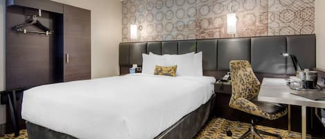 Habitación de hotel con una cama grande, un escritorio con una silla, un armario y una pared con diseño.