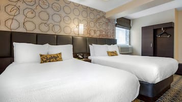 Habitación de hotel con dos camas, un ventanal grande, un armario y una pared con diseño.