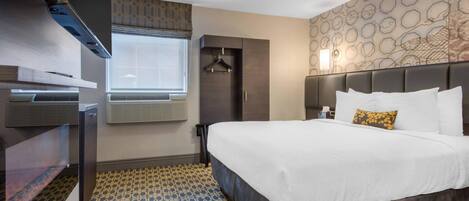 Habitación de hotel con una cama grande, un armario, un calefactor, una ventana con persianas y una alfombra estampada.