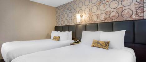 Habitación de hotel con dos camas, un papel tapiz estampado y un cabecero moderno.