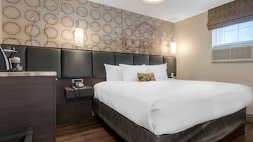 Une chambre d’hôtel avec un grand lit, une table de chevet avec un téléphone, une lampe et un mur orné d’un motif géométrique.