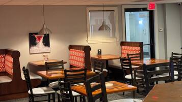 Un interior de restaurante con cabinas y mesas, sillas de madera y un cuadro enmarcado en la pared.