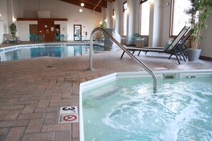 An indoor swimming pool with a brick floor, lounge chairs, and a no diving sign. - Schoenbrunn Inn (New Philadelphia)