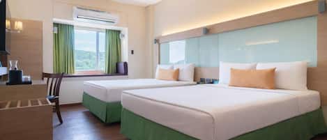 Ein Hotelzimmer mit zwei Betten, einem Schreibtisch und einem Fenster mit Vorhängen.