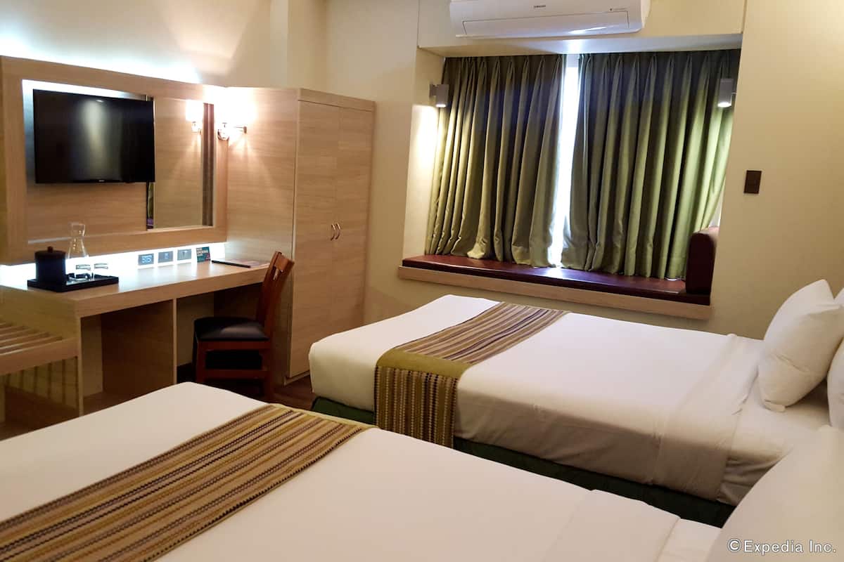 A hotel room with two beds, a desk with a chair, a television, and a window with curtains.