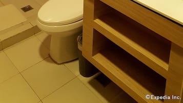 Un bagno con il water, un lavandino, una doccia e uno scaffale con articoli da toilette.