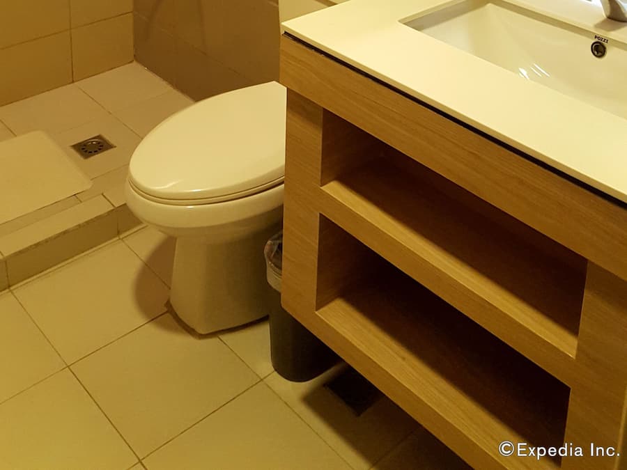 A bathroom with a toilet, a sink, a shower, and a shelf with toiletries.