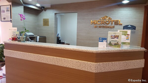A reception desk at a hotel with a sign that reads "MICROTEL BY WYNDHAM". - Microtel by Wyndham Baguio (Baguio)