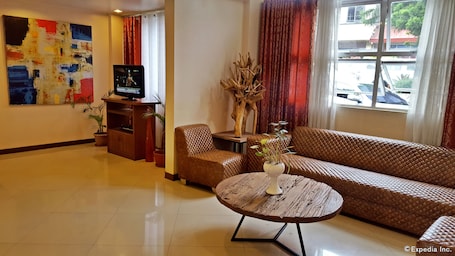 A living room with a sofa, a coffee table, a television, and a painting on the wall.