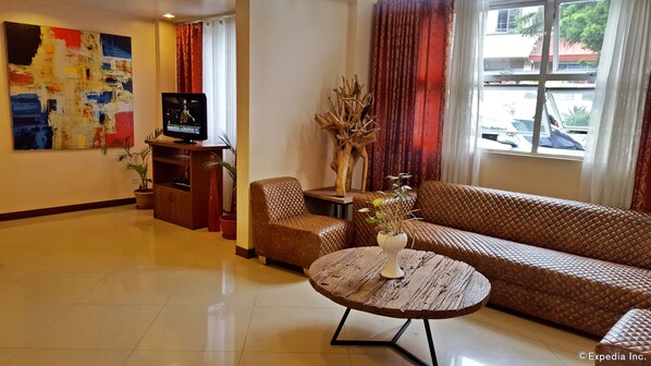 Una sala de estar con un sofá, una mesa de centro, un televisor y un cuadro en la pared.