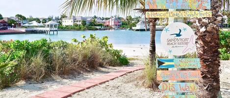A beach signpost with multiple directional signs and a logo for Sandypoint Beach Resort.
