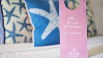 A pink tag with text and a starfish logo, placed on a textured surface with a blue pillow in the background.