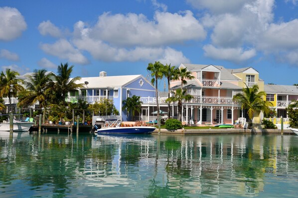 A waterfront property with a boat dock, a pool, and a building with a balcony. - Sandyport Beach Resort (Nassau)