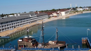 A waterfront hotel with multiple balconies, a beach area with sun loungers, and a dock with boats. - Hamilton Inn Select Beachfront Mackinaw City (Mackinaw City)