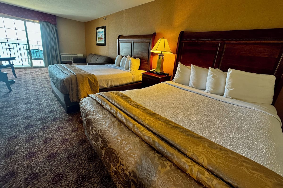 A hotel room with two beds, a desk, and a chair.