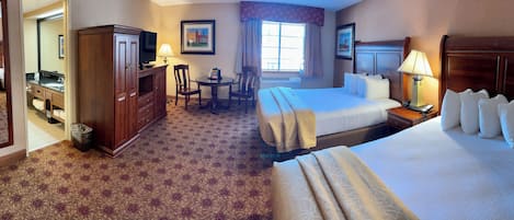 A hotel room with two beds, a desk, a chair, a TV, and a bathroom.