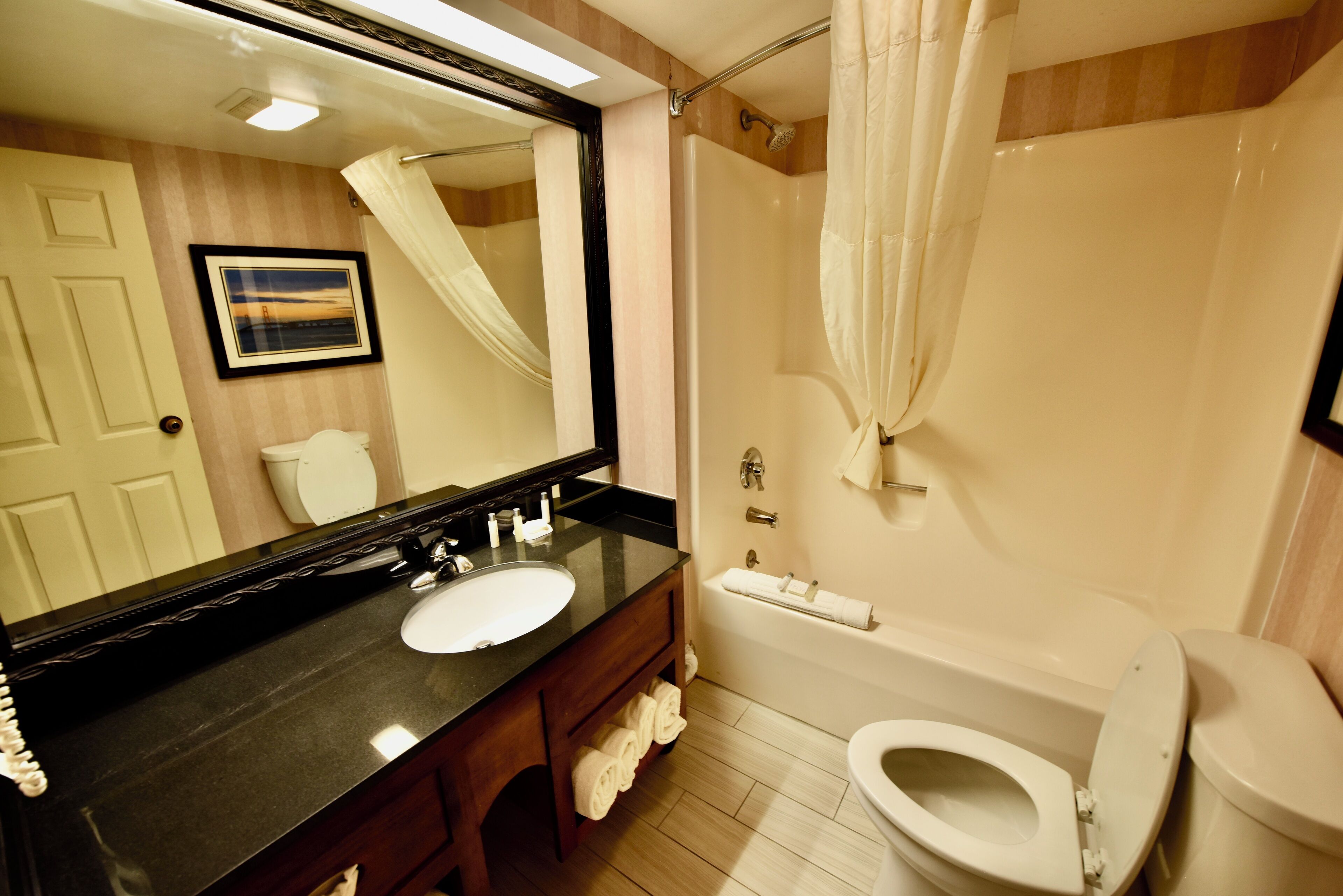 Un baño con lavamanos, espejo, inodoro y bañera.