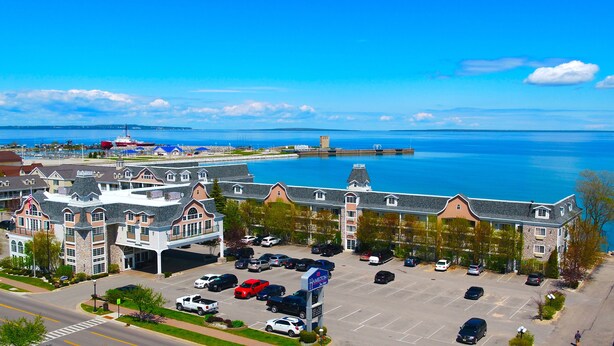 A waterfront hotel with a parking lot, a view of the sea, and a distant island. - Hamilton Inn Select Beachfront Mackinaw City (Mackinaw City)